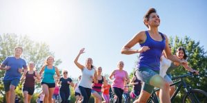 People exercising outdoors in a sunny, green environment.